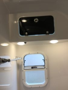 In an RV bathroom. The tiny window is on the bottom half while the black door of a tiny cabinet is above. In this Oliver Travel Trailer review, the cabinet is much too small to hold all that's needed.