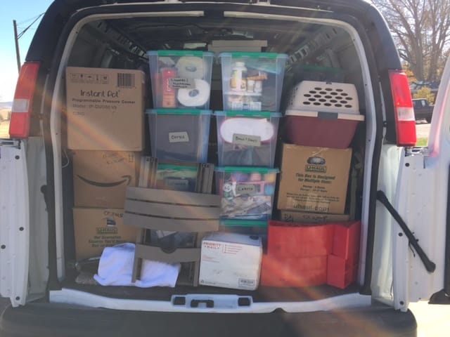 A van with the back doors open, filled with boxes and storage bins.