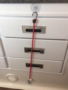 White drawers held in place with bungee cord.