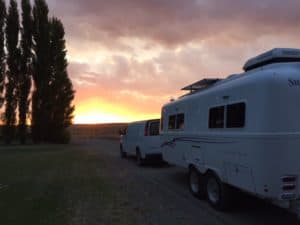Travel trailer and van in a vineyard at sunset.