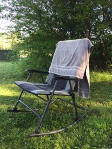 Gray towel draped over a camp chair, sitting in the grass.