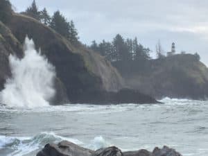 Lighthouse on a cliff overlooking the ocean with crashing saves.