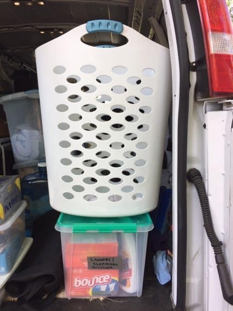 Plastic laundry hamper on top of a plastic storage bin.