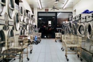 Empty laundry mat with lots of washers and dryers. Photo by Bianca Jordan on Unsplash.