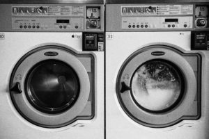 White and gray coin-operated washer and  dryer next to each other.