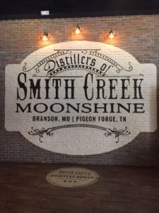 Brick wall with the logo for Smith Creek Moonshine panted on it.