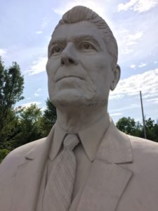 Large concrete statue of President Reagan's head against the blue sky. Sitting in a parking lot in Branson, Missouri.