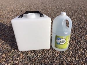 Plastic tank next to a big bottle of white vinegar.