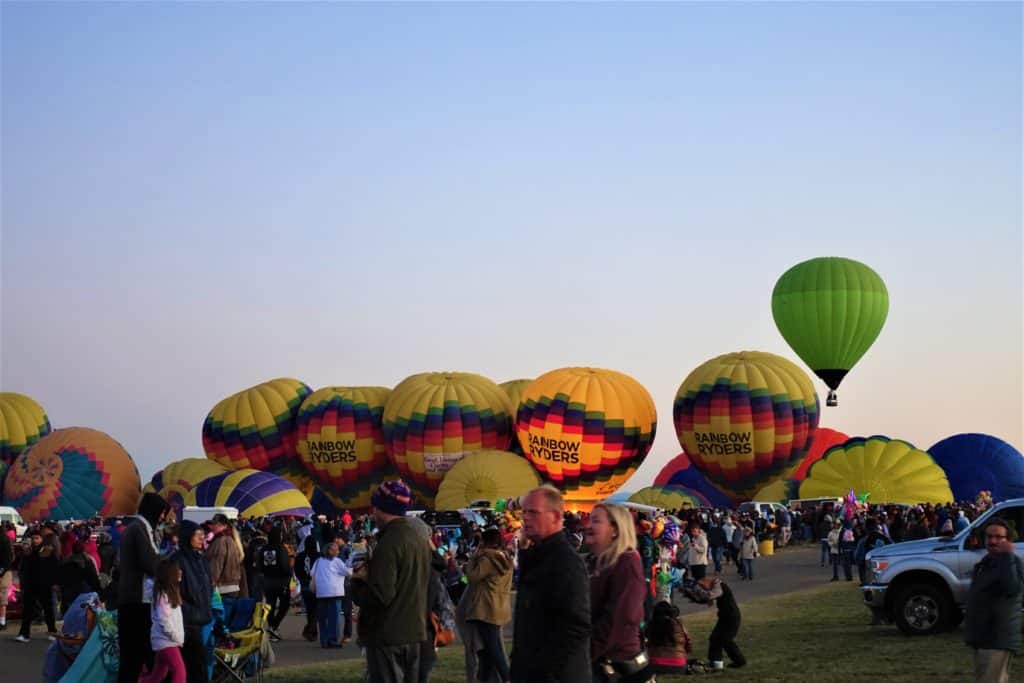 A line of yellow hot air balloons in the process of inflating at the Albuquerque Balloon Fiesta launch field in the predawn. 