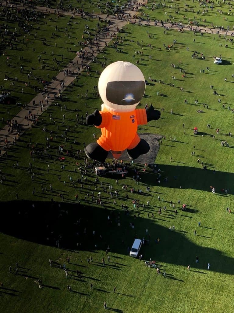 Hot air balloon on the ground  that looks like an astronaut with orange suit and white helmet. Taken from just above the ground.
