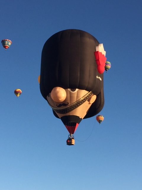 Hot air balloon with a person's face and a black hat that goes halfway down the eyeballs.