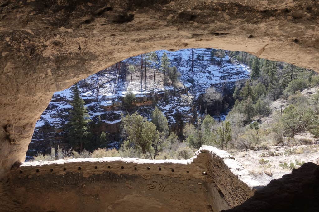 A view from inside a cave, looking out into the trees and rocks below.