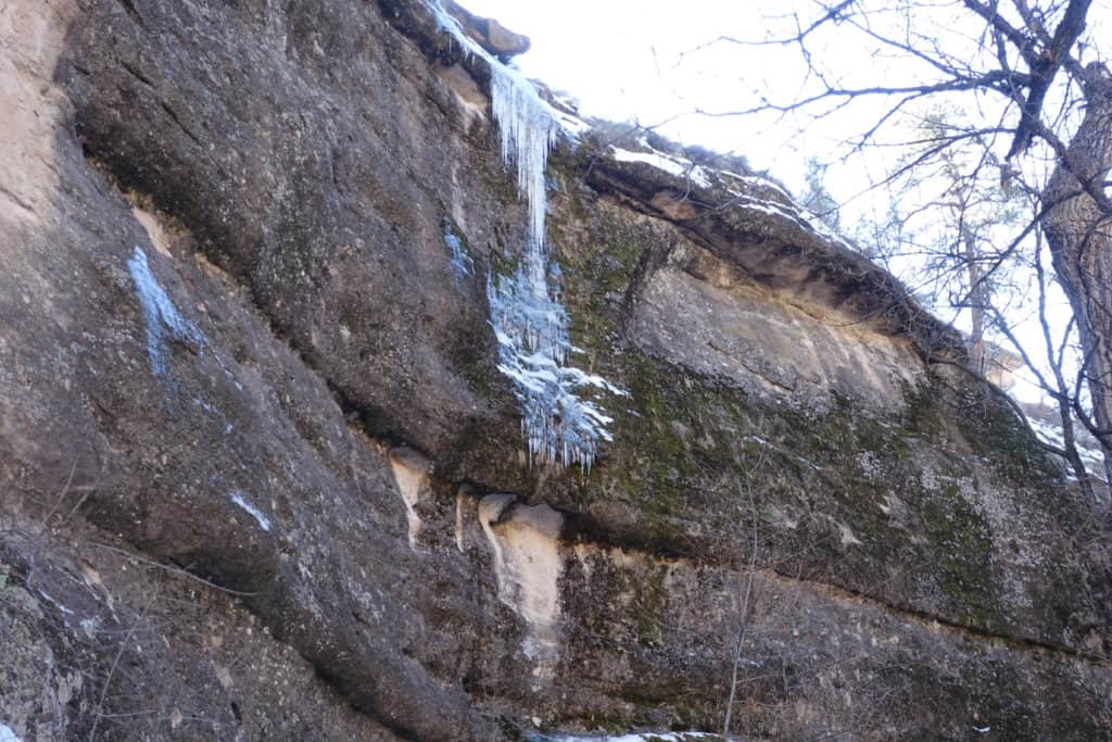 Close up of a vertical rock of a canyon with ice and icicles.   