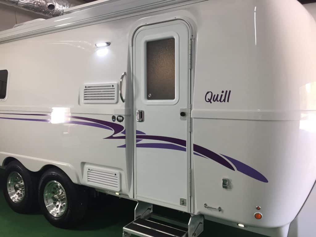 Side view of a white Oliver Travel Trailer with purple swoosh graphics.