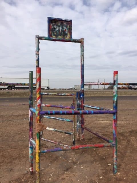 A metal gate painted in many different colors.