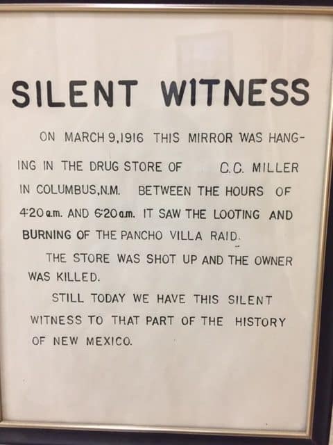 A photo of an information sign that reads, "Silent Witness. On March 9 1916 this mirror was hanging in the drug store of CC Miller in Columbus, NM. Between the hours of 4:20 a.m. and 6:20 a.m. it saw the looting and burning of the Pancho Villa Raid.

The store was shot up and the owner was killed.

Still today we have this silent witness to that part of history of New Mexico.