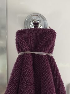 Purple towel over a silver hook, secured by a clear rubber band.