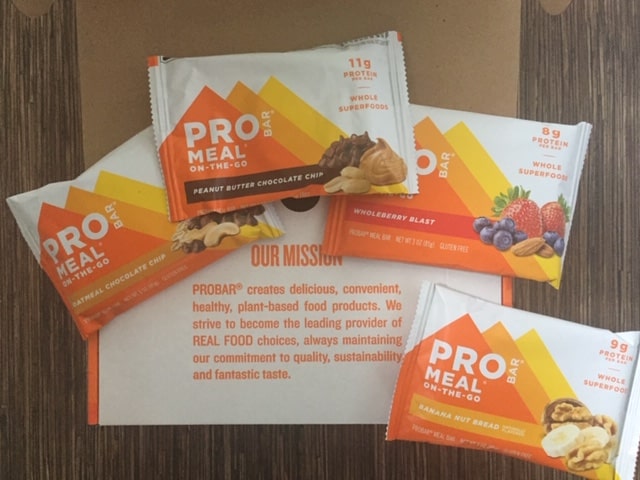 Box of ProBar Meal with four bars sitting on top. They are positioned so you can read the mission statement on the box.