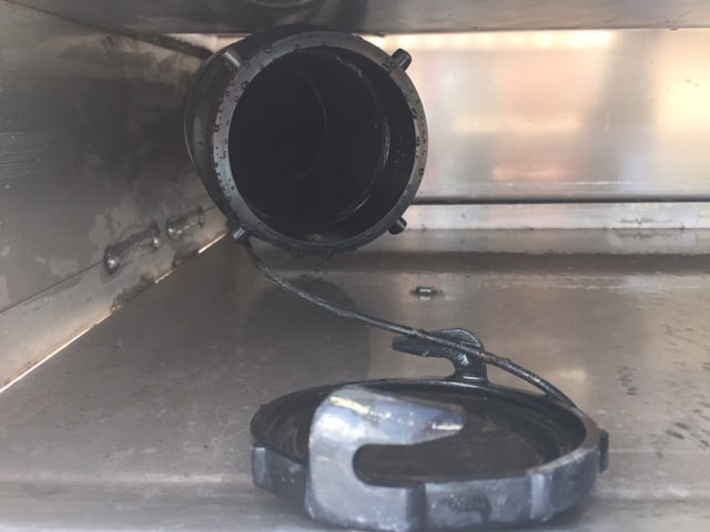 Inside a silver bumper, photo is a close up of the place were an RV sewer hose is attached. The tube is 3" black round.