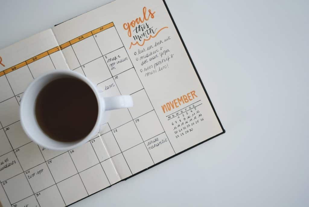 Cup of coffee on a monthly planner. Photo by Estée Janssens on Unsplash.