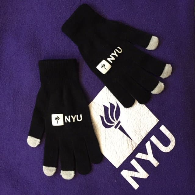 A purple blanket with the NYU logo as well as a pair of black glove with the same logo.