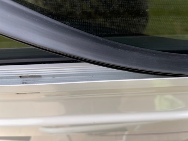 A close up of the black strip of window seal as it's being laid in the window frame of an RV.