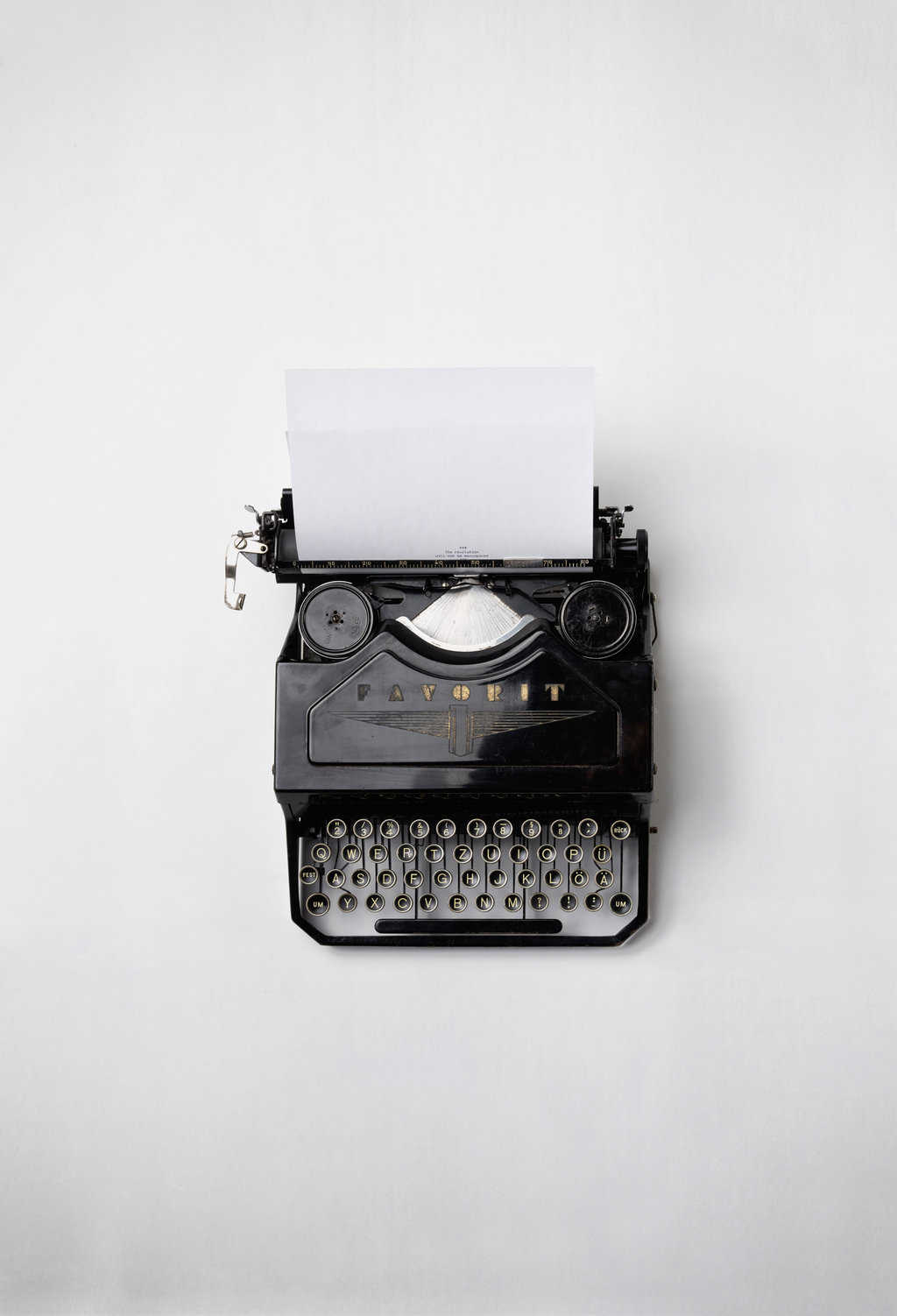 An old black typewriter against an all white background.