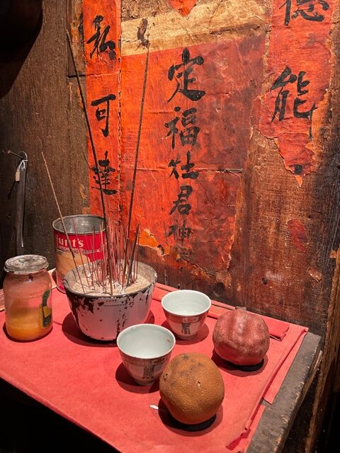Chinese altar with Chinese characters, incense and old fruit.