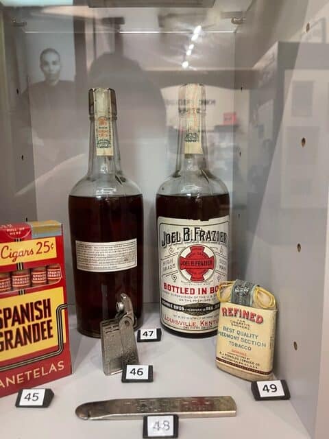 Two old whiskey bottles, old tobacco in a display case.