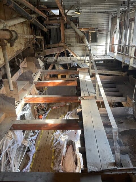 Upper level inside a wooden dredge. Lot of uneven and broken boards.
