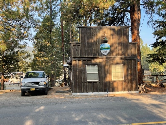 A small wood building with the Oregon State Park seal. A white pickup truck parked next to it.