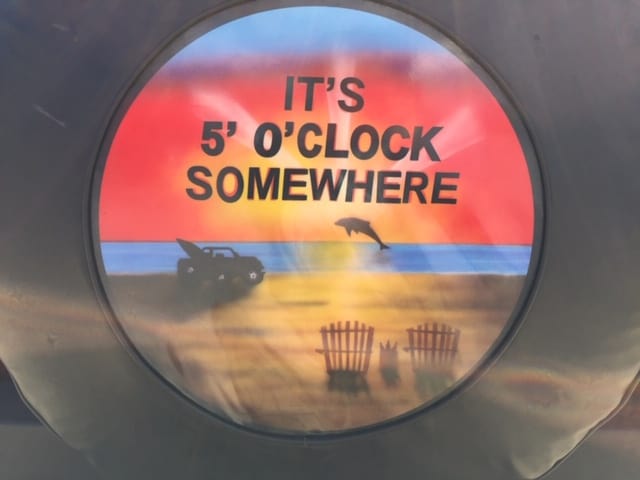 RV tire cover with beach scene, dolphin and an RV that reads It's 5 O'Clock Somewhere.  