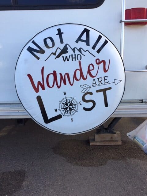 RV tire cover with mountains and a compass that reads Not All Who Wander Are Lost.  