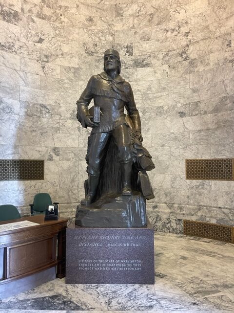 Bronze statue of a man carrying a book.