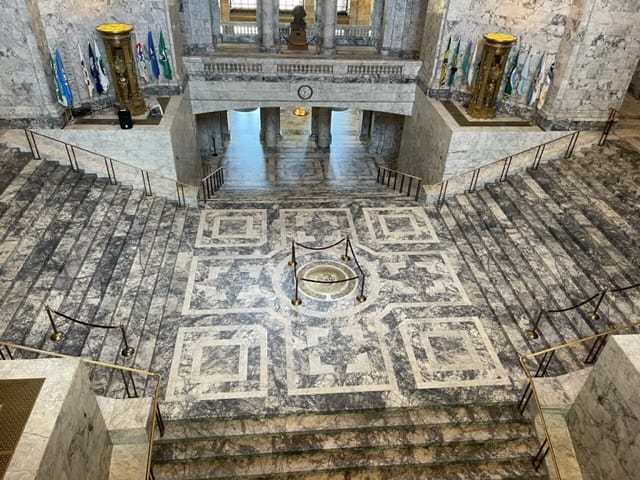 Looking down to the floor below of the rotunda. The floor and staircases are all black and white marble.